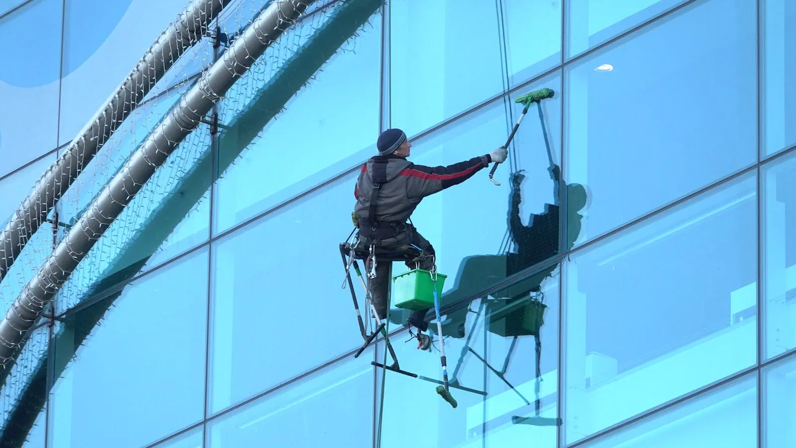 Window cleaner working on a high-rise glass building with professional pole-mounted equipment ensuring spotless results